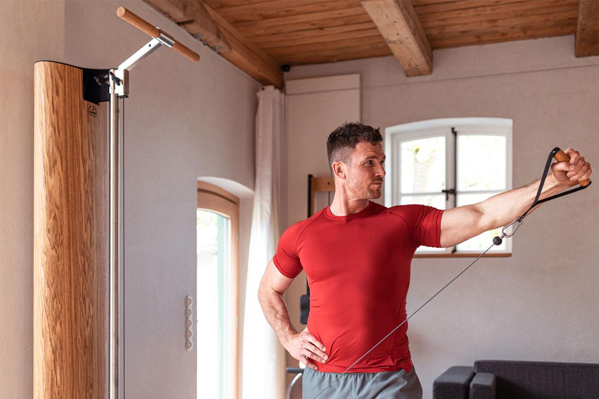 Mann trainiert mit NOHrD Seilzuggerät in einem Raum.