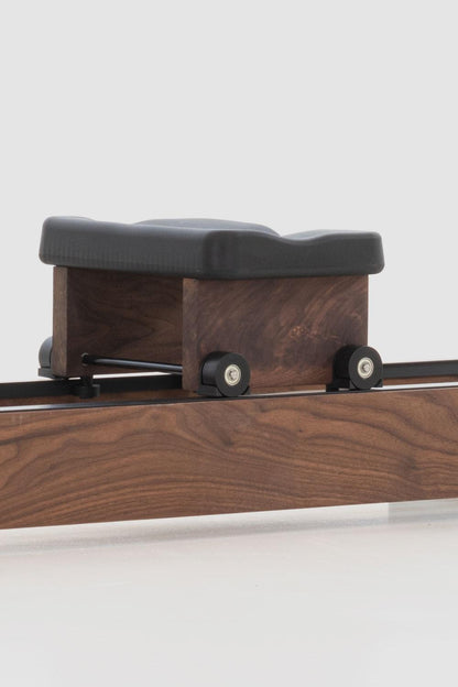 Holz-Rudergerät mit schwarzem Sitz und Rollen auf Schiene.