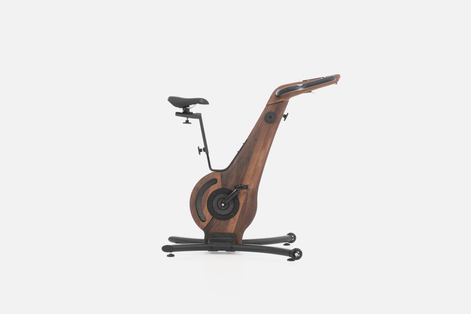 Holz-Design Heimtrainer mit Sattel und Pedalen, seitliche Ansicht.