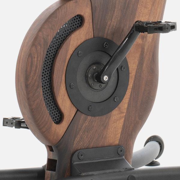 Holzverkleidetes Fitnessgerät mit Pedalen und schwarzem Metallrahmen.