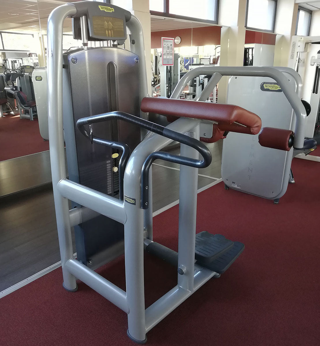 TechnoGym Gluteus Machine, Glute, Selection Line - New model with plastic cover, brown upholstery, used - refurbished condition